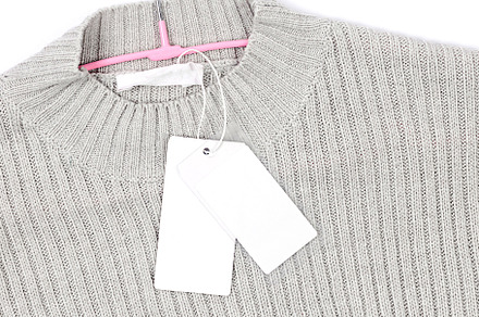White empty Clothing Tag on a gray sweater, a Background Photo by vimart