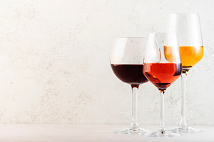 Red, rose and white wine glasses set on gray table background. W