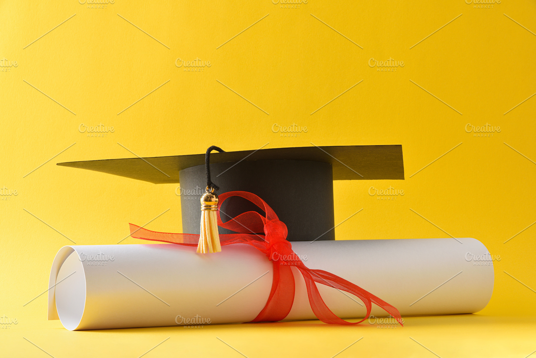 Academic cap and diploma with red ribbon isolated on yellow, a School & Education Photo by Davizro's Market