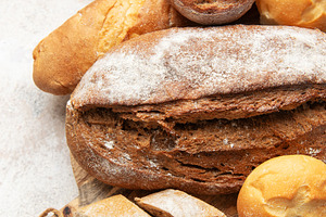 Assortment of fresh baked bread on rustic wooden board, a Food & Drink Photo by Olena Rudo