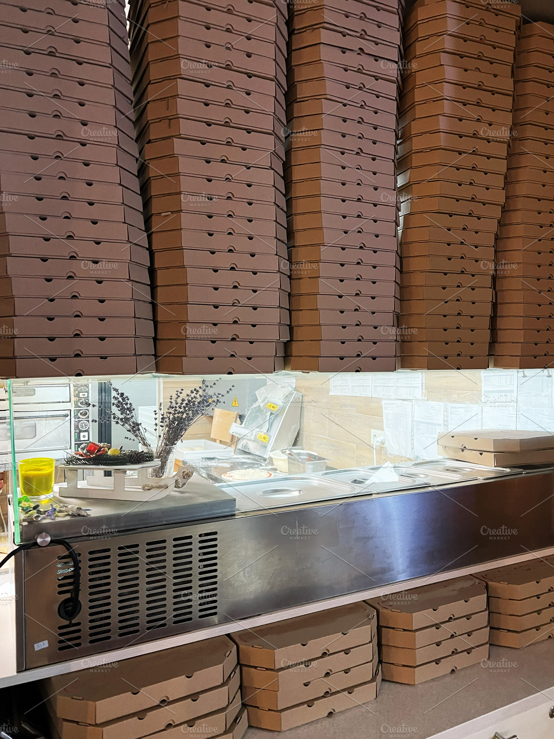 Stacked pizza boxes in a pizzeria kitchen showcasing preparation and storage, a Photo by AS photostudio