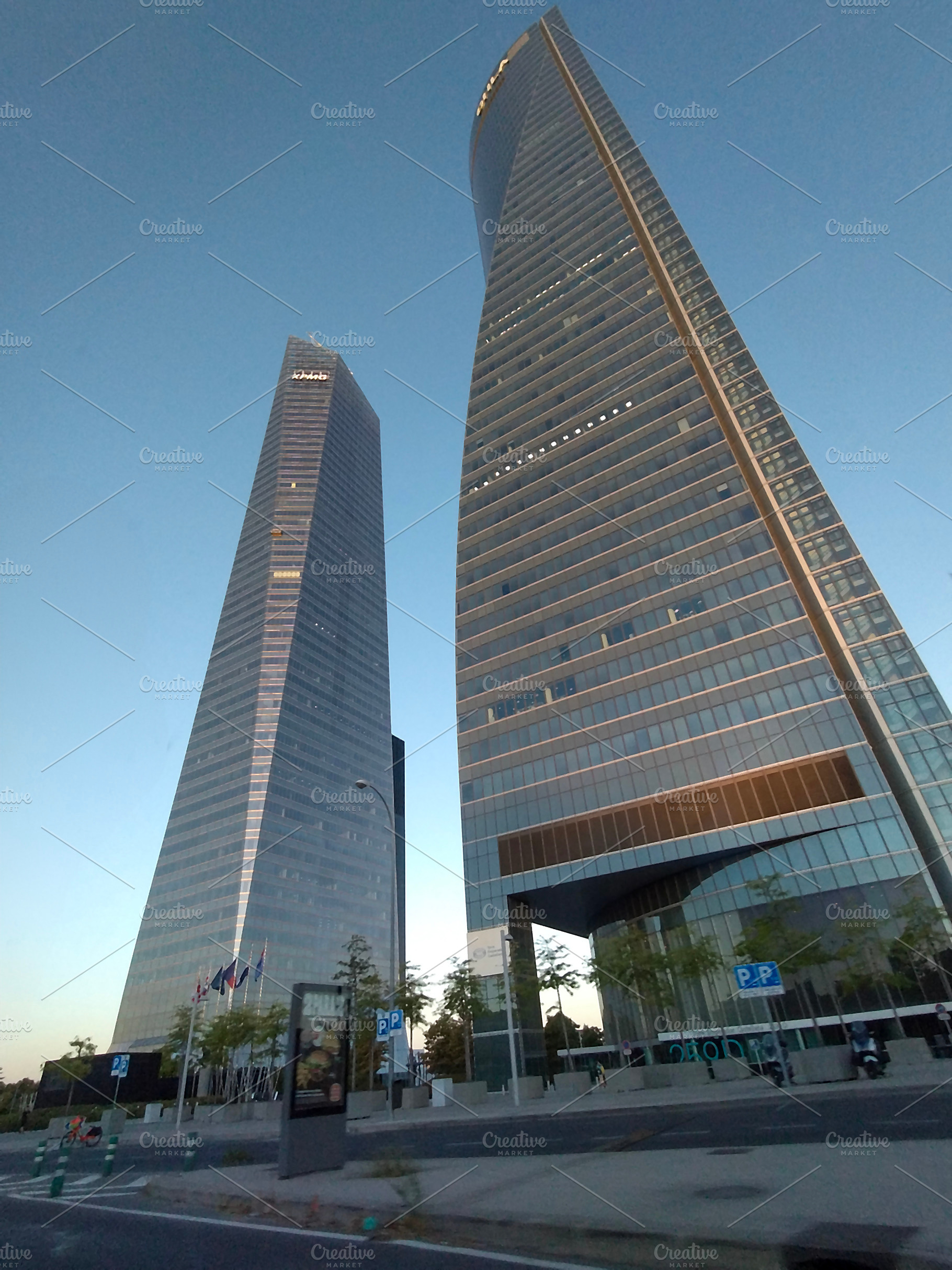 Tall skyscrapers with reflective glass under blue sky, an Architecture Photo by DanFLCreativo