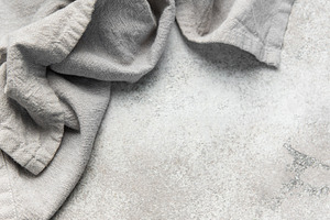 Wrinkled grey linen fabric resting on stone background, a Food & Drink Photo by Olena Rudo
