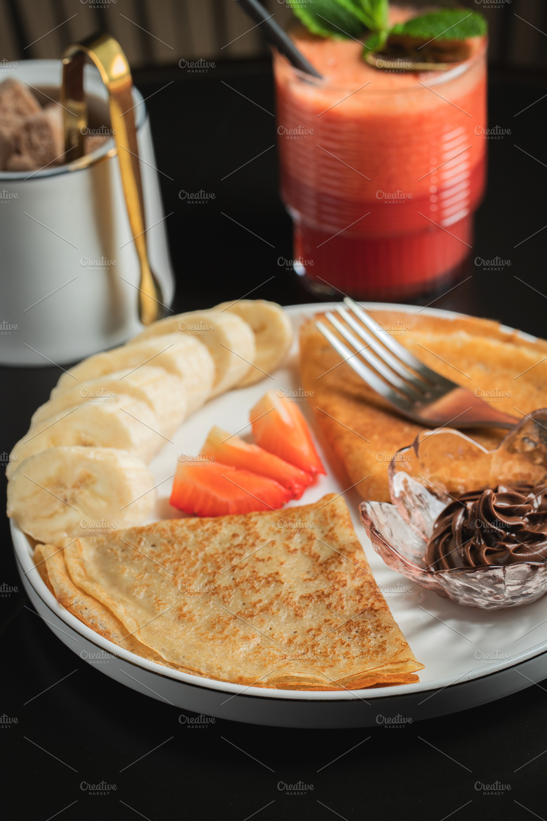 A plate of crepes filled with chocolate spread and topped with banana slices an, a Food & Drink Photo by Budarinphoto
