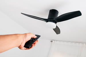 man operating a ceiling fan with remote control, a Photo by Nito