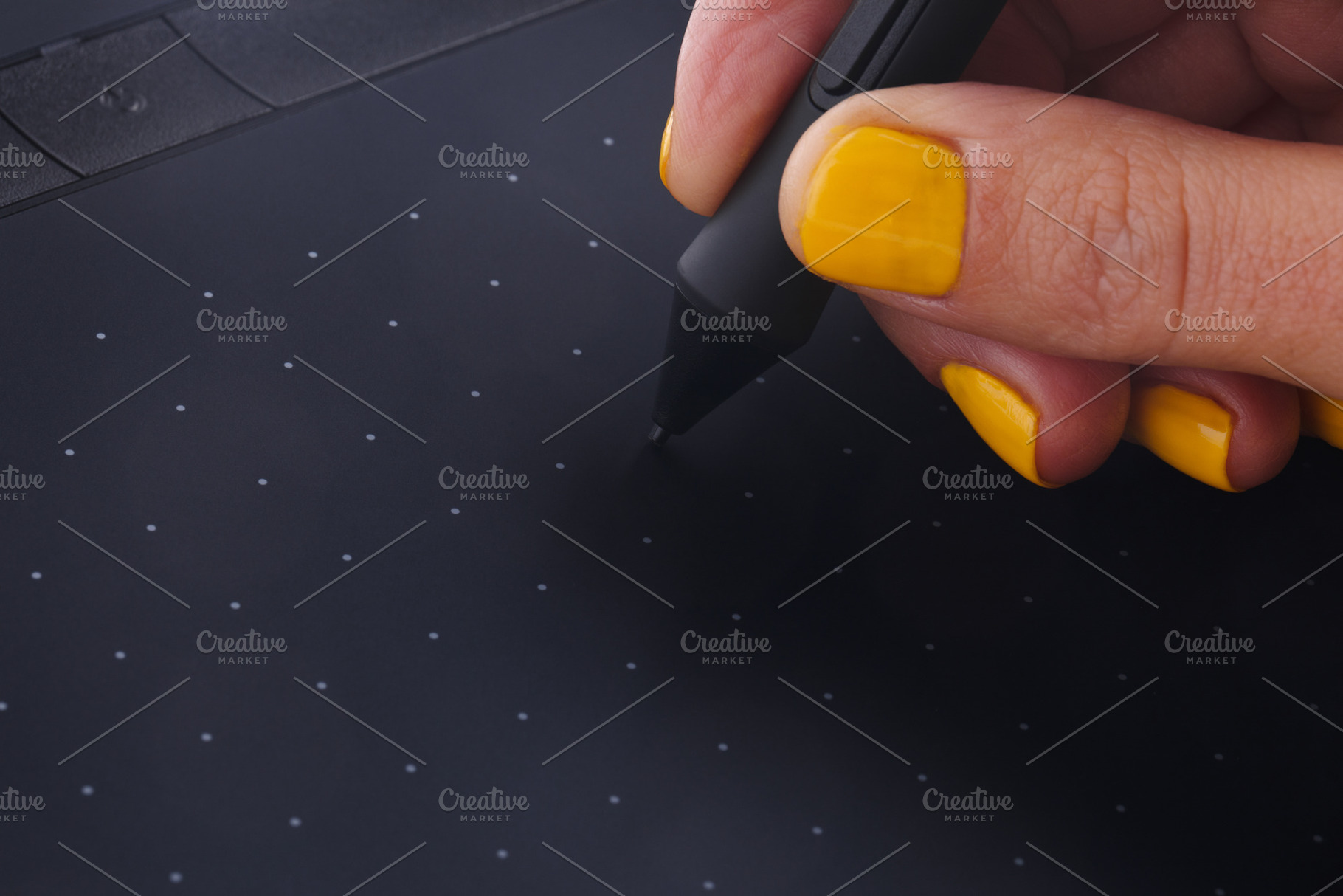 Close-up of a hand with yellow nails using a stylus on a digital, a Technology Photo by Ales Munt