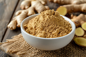 Ground dry ginger in bowl on wooden background, a Food & Drink Photo by AlyaAnd