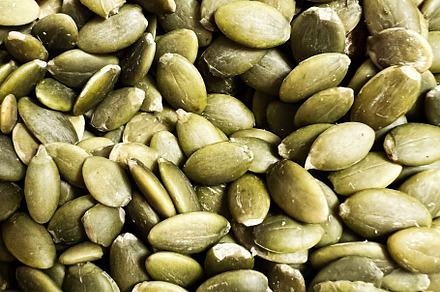 Close-up of raw green pumpkin seeds displayed on a neutral background, a Photo by AS photostudio