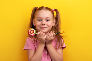 Smiling young girl in pink shirt holding colorful fruit lollipop, a Person Photo by Ales Munt