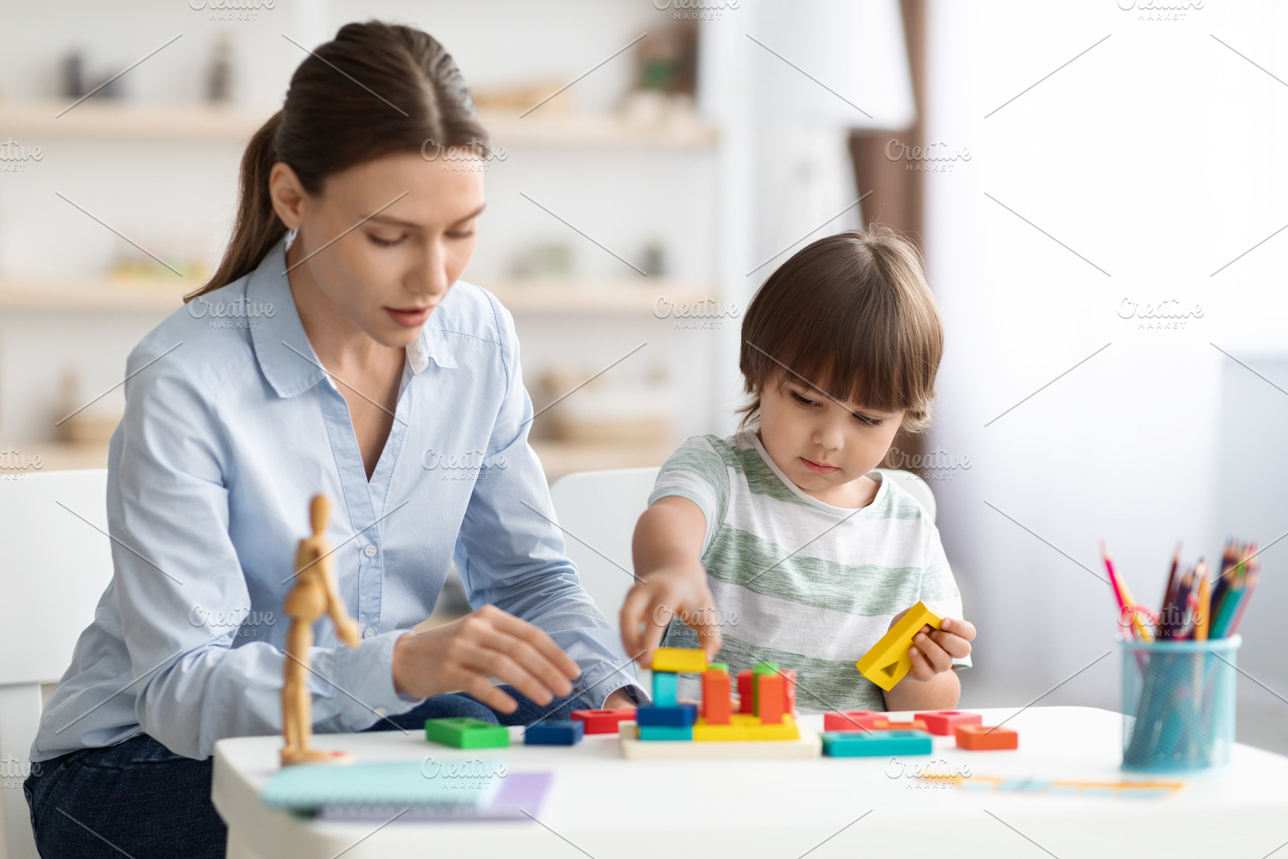 Cute little boy preschooler playing developing wooden games with professional w, a Photo by Prostock-Studio