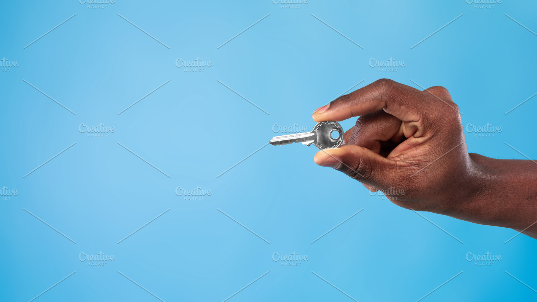 Unrecognizable young black man holding metal house key on blue studio backgroun, a Photo by Prostock-Studio