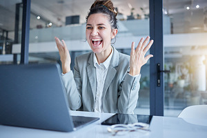 Happy, success and successful businesswoman celebrating in an office  and working on a laptop excited for achievement. Celebration, celebrate and corporate employee winning at her goal or promotion, a Photo by Peopleimages.com