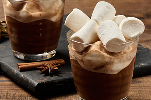 Glasses of hot chocolate with fluffy marshmallows on a wooden ta, a Food & Drink Photo by ndanko