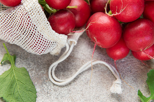 Fresh red radishes with green leaves in a reusable mesh bag, a Food & Drink Photo by Olena Rudo