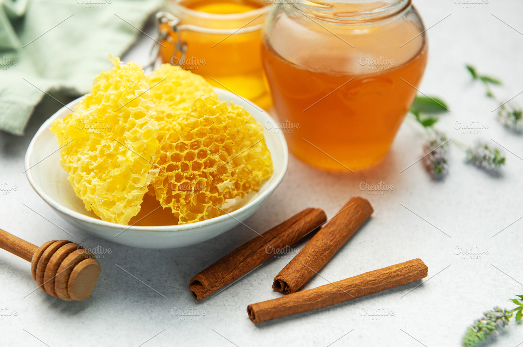 Honeycomb, honey jar, cinnamon sticks, and honey dipper resting, a Food & Drink Photo by Olena Rudo