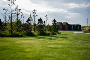 Modern cabins near green landscape with trees under cloudy sky, a Photo by AS photostudio