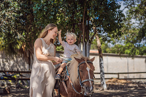 Excited toddler enjoys a pony ride, a Person Photo by Elizaveta Galitskaya