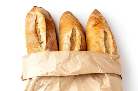 Freshly baked baguette in paper bag isolated on white background, a Food & Drink Photo by AlyaAnd