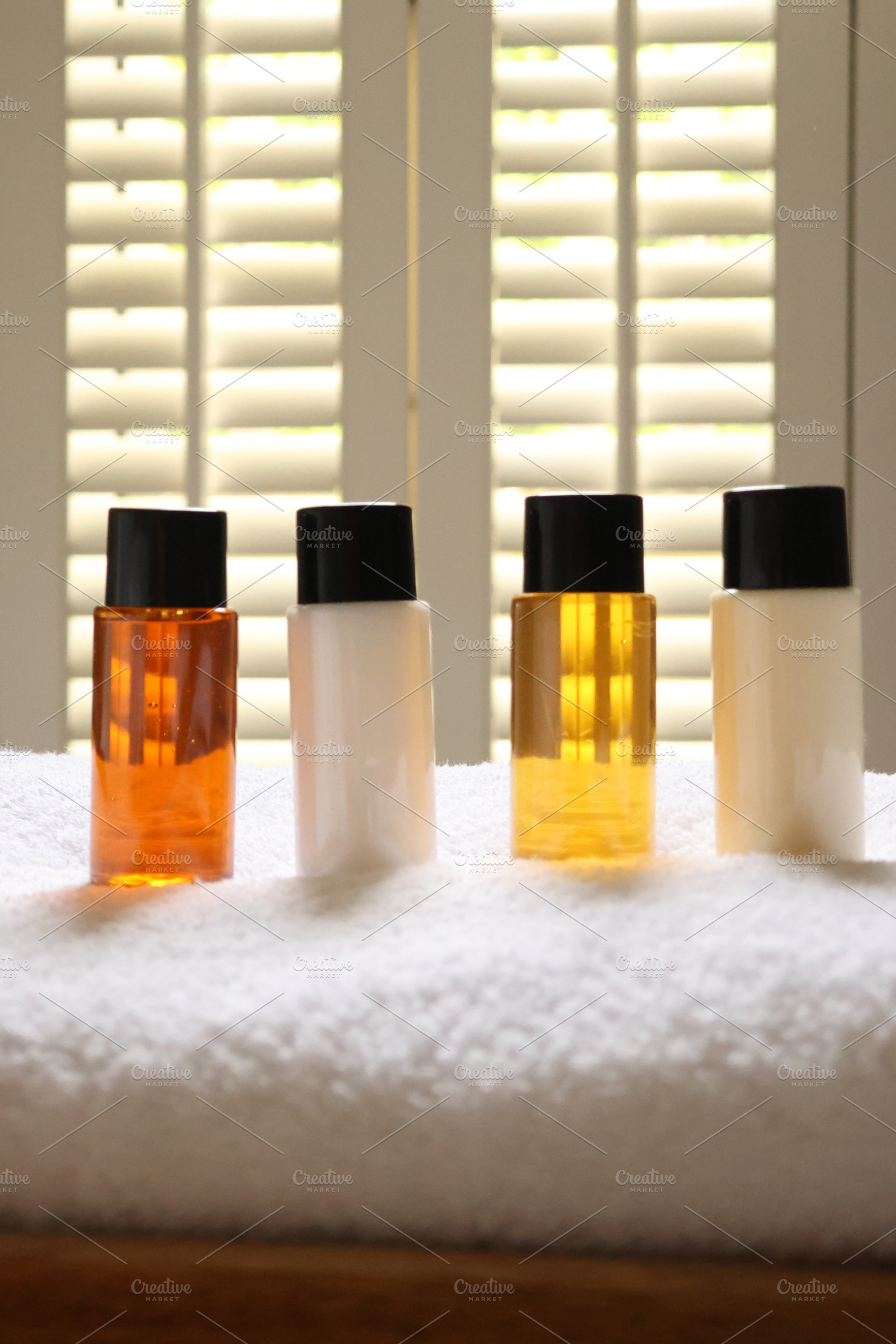 Travel size toiletries arranging on white towel in hotel bathroo, a Photo by Studio ANNA