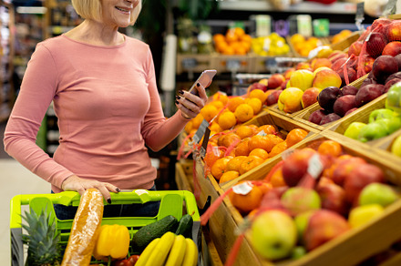Cropped of senior woman using smartphone while shopping at supermarket, a Person Photo by Prostock-Studio