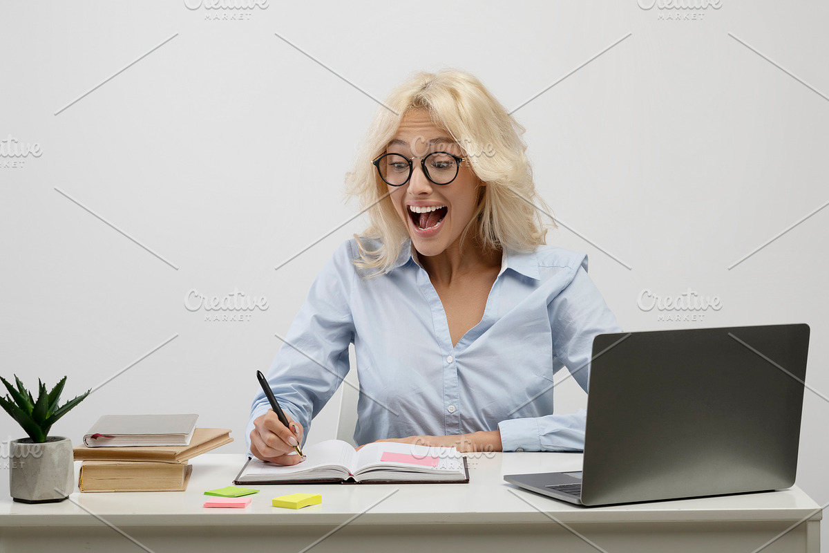 Surprised businesswoman working on laptop and taking notes in notebook, surpris, a Photo by Prostock-Studio (Photo 2 of 2)