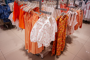 Colorful assortment of children clothing displayed on racks in a retail store, a Photo by AS photostudio