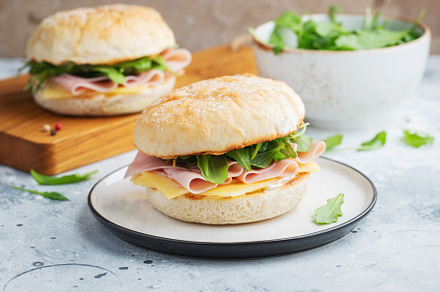 Two homemade sandwiches with ham, cheese and arugula on a concrete table., a Food & Drink Photo by Budarinphoto