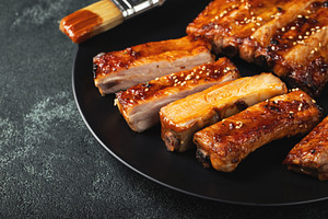 Hot grilled spare ribs from a summer BBQ served on a plate with sauce. Top view, a Food & Drink Photo by Budarinphoto