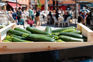 crate with zucchinis for sale at farmers market, a Photo by Nito