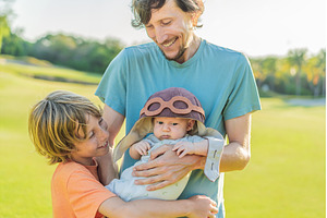 Father, son, and newborn on a meadow, a Holiday Photo by Elizaveta Galitskaya
