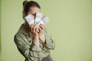 Woman hides behind wealth: Stacks of hundred bills, a Business Photo by Alliance Images