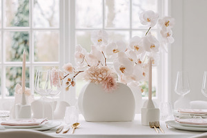 Sophisticated table setting featuring a centerpiece of white orc, a Photo by Studio ANNA