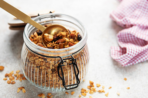 Granola cereal with nuts in a glass jar and spoon, healthy break, a Food & Drink Photo by Olena Rudo