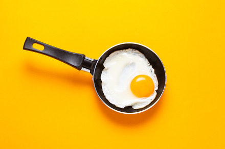 Scrambled, frying  eggs from one egg in a small pan on yellow ba, a Food & Drink Photo by MDBildes