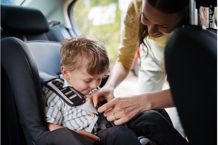 Young mother buckling toddler into, a Transportation Photo by HalfPoint