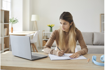 Student sitting at desk with laptop, a School & Education Photo by StudioRomantic