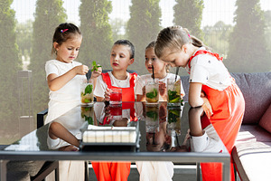Group of children enjoying fresh beverages together in a bright outdoor setting, a Photo by AS photostudio
