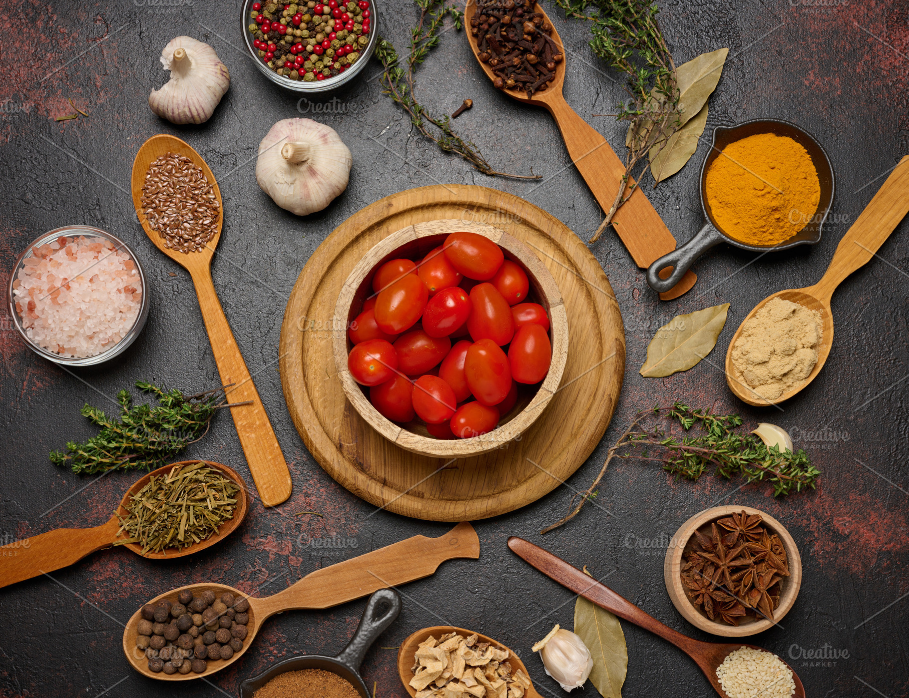 Cherry tomatoes in a wooden bowl and various spices on a dark ta, a Food & Drink Photo by ndanko