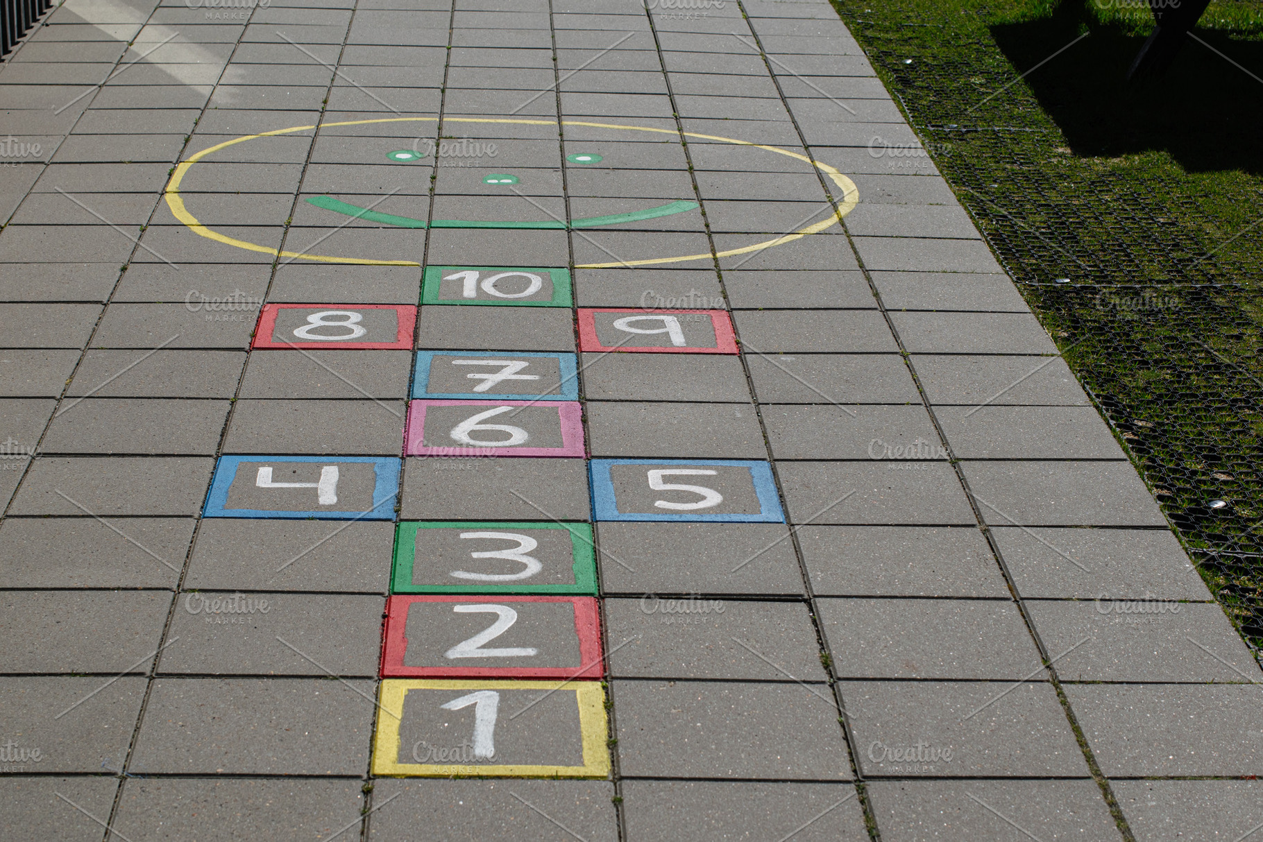 Colorful hopscotch game on pavement in Akranes, Iceland under sunlight, a Photo by AS photostudio