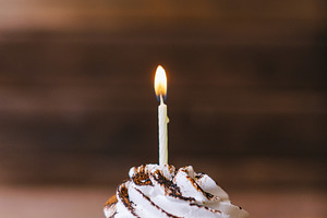 Cream cupcake with one candle. 