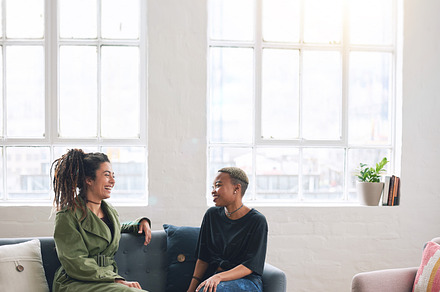 two woman friends talking having conversation sitting on sofa at home, a Photo by Peopleimages.com