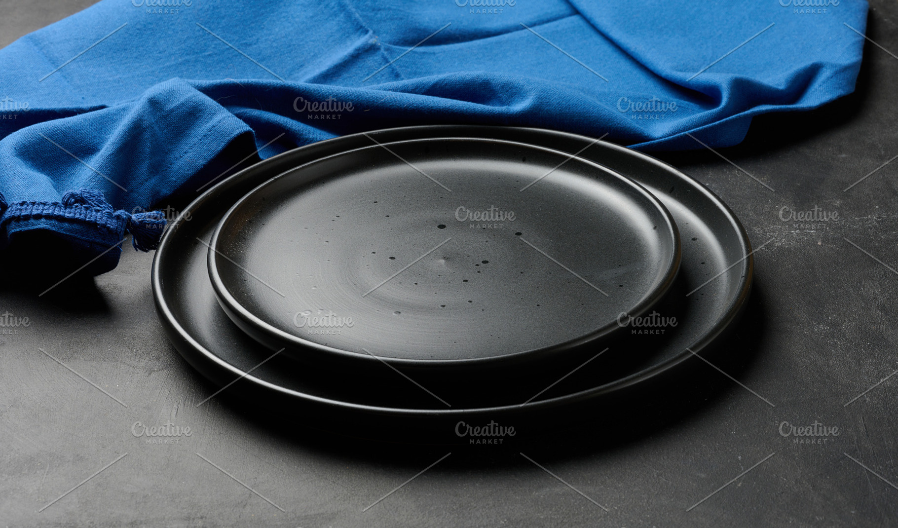 Empty black ceramic plates stacked on dark background with blue, a Food & Drink Photo by ndanko