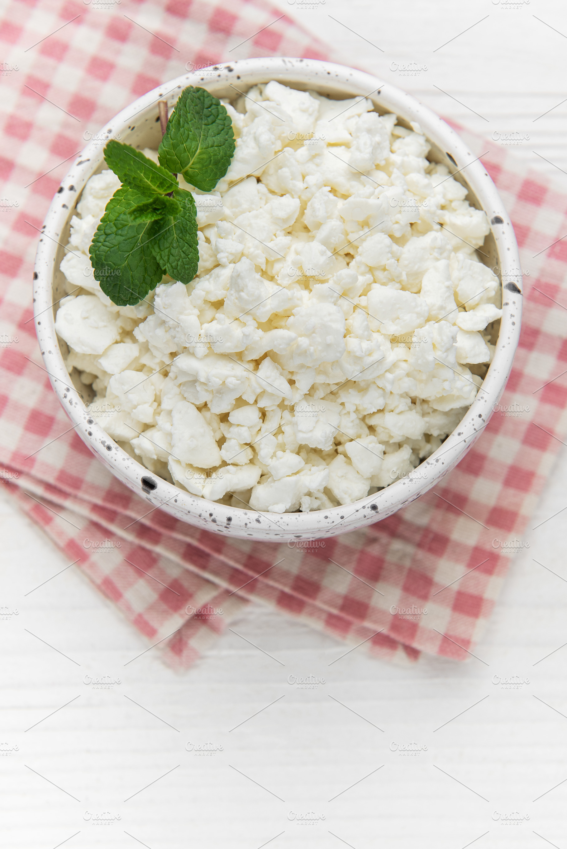 Cottage cheese in bowl with mint leaves on checkered napkin, a Food & Drink Photo by Olena Rudo