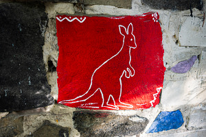 Kangaroo-shaped painting on a stone wall with a vibrant red background, a Photo by AS photostudio