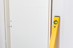 Yellow spirit level leaning against white door during installation, an Architecture Photo by Antonio Gravante Market