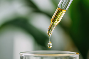 Close-up of dropper releasing amber liquid, a Health & Medical Photo by AlyaAnd