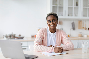 Glad millennial african american female in glasses work or study at laptop at w, a Person Photo by Prostock-Studio