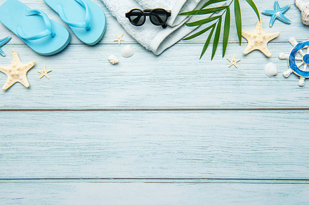 Summer accessories creating a frame on light blue wooden backgro