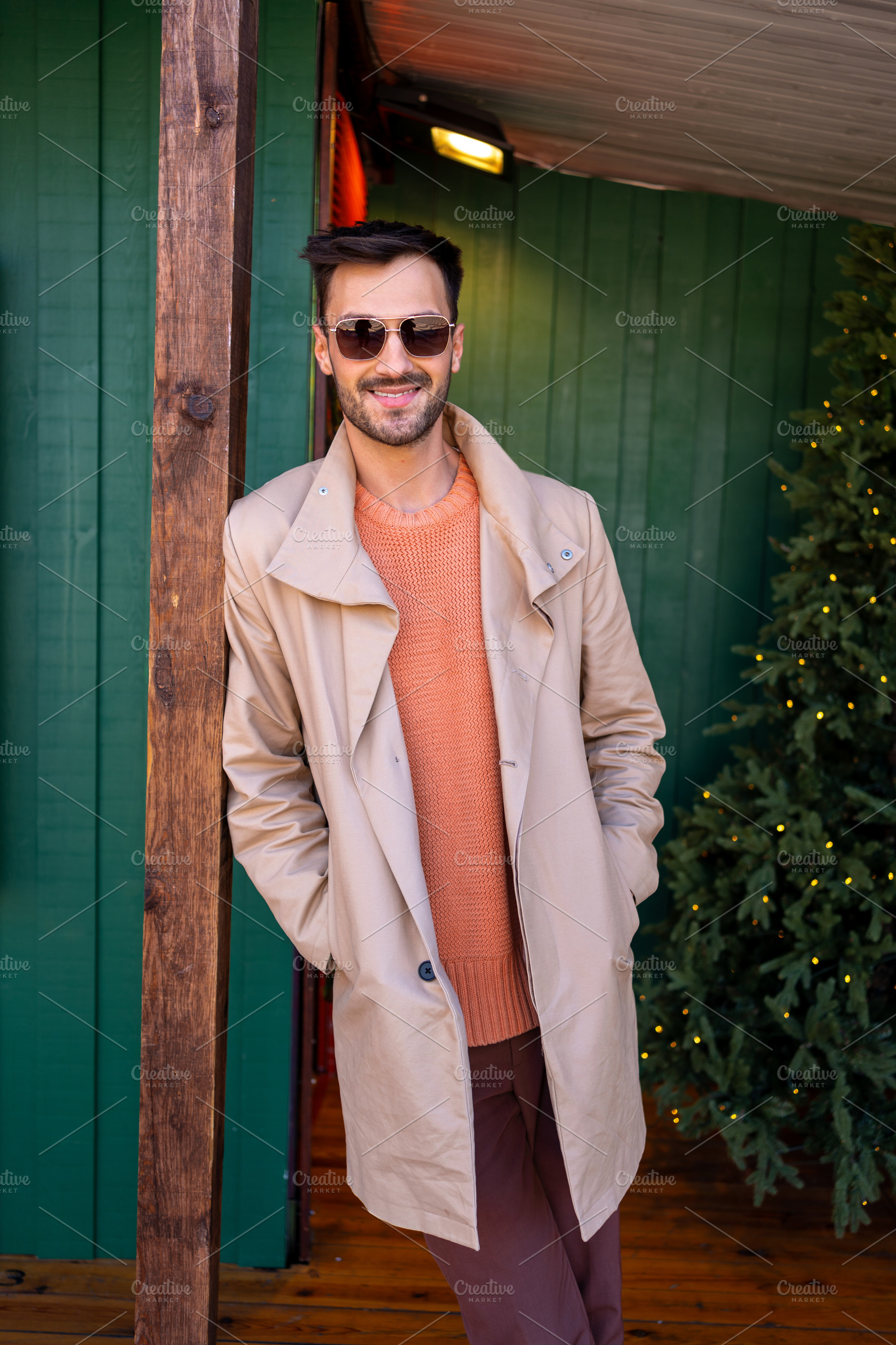 Handsome man in beige trench coat standing with hands in pockets, a Person Photo by andreonegin market