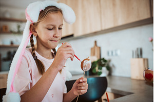 Girl with bunny ears paiting eggs, a Holiday Photo by HalfPoint